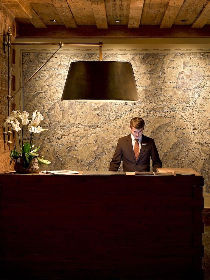 Concierge at a wood reception desk in front of a map wall